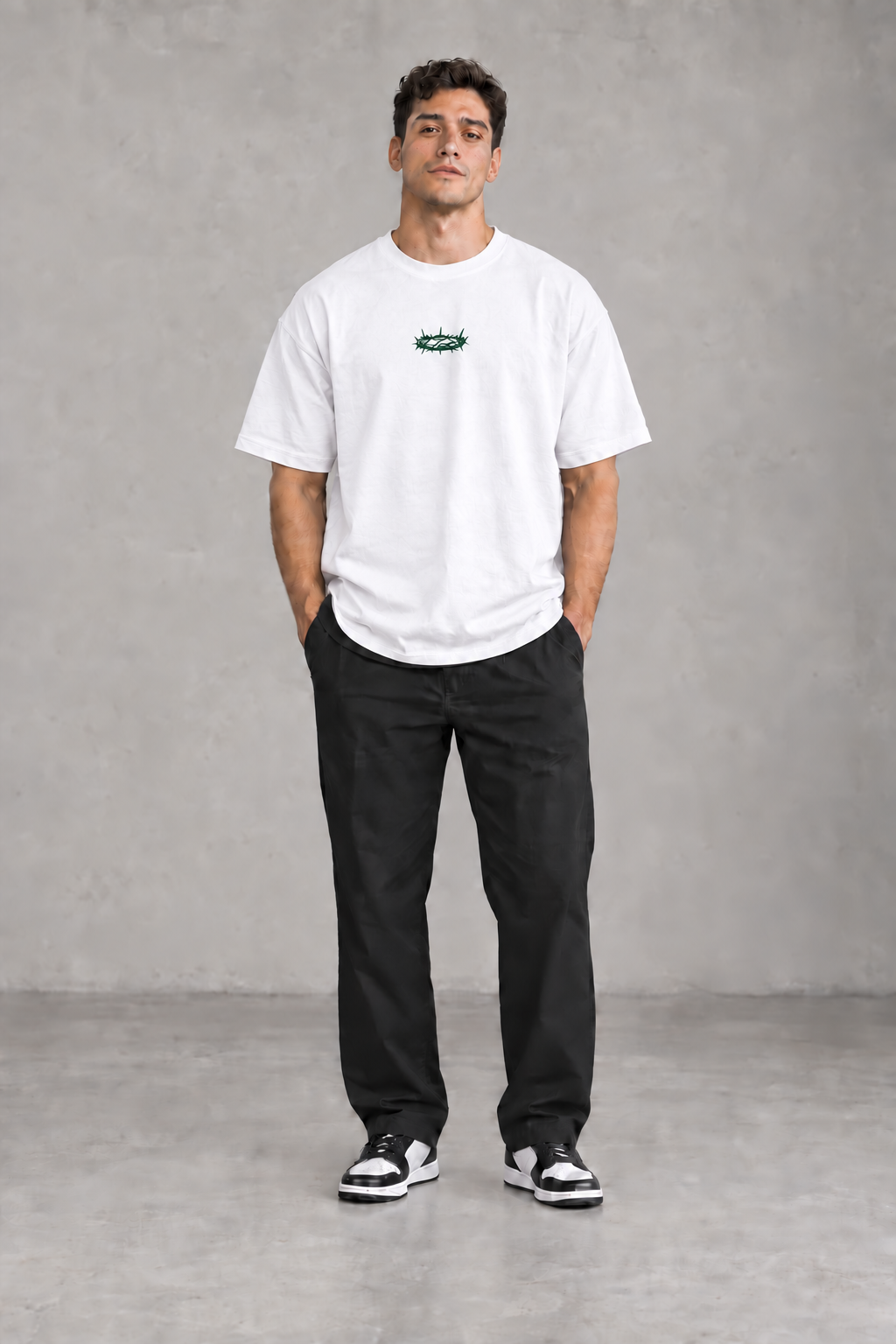 Männliches Model mit weißem GRÖSSTE LIEBE Signature-T-Shirt und mittiger dunkelgrüner Dornenkrone von vorne